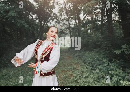 Une femme en vêtements traditionnels turkiques orientaux brodés exécute une danse nationale dans le parc Banque D'Images