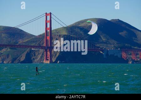 Kite surfeur ou kiteboarder avec voile blanc sur une journée venteuse devant le Pont du Golden Gate et les Marin Headlands, baie de San Francisco. Banque D'Images