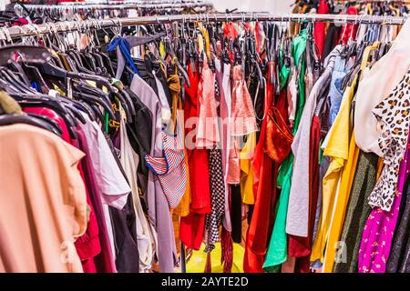 Section de dégagement bondée dans un magasin de vêtements, avec divers vêtements colorés placés étroitement sur des racks dans un ordre particulier; concept de mode rapide Banque D'Images