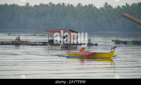 Banay Banay Banay, Davao Oriental, Philippines - mars 2016 : un bateau à outrigger jaune s'éloigne des parcs à poissons du village de pêche de Punta Linao dans l'SO Banque D'Images