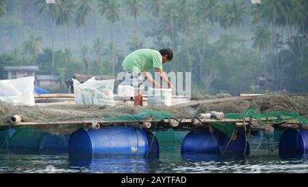 Banay Banay Banay, Davao Oriental, Philippines - mars 2016 : un homme prépare des aliments à partir de stylos de pêche flottants dans la partie sud des Philippines. Banque D'Images