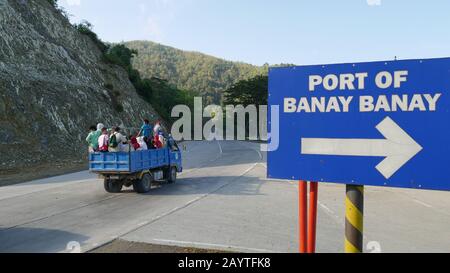 Banay Banay, Davao Oriental, Philippines - Mars 2016: Panneau de signalisation routière en direction du port de Banay Banay avec un camion rempli de passagers tra Banque D'Images