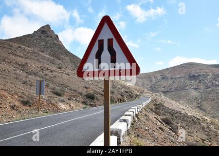 Panneau triangulaire de rétrécissement de route sur route de montagne avec montagne en arrière-plan. La route passe clairement de deux voies à une voie unique. Banque D'Images