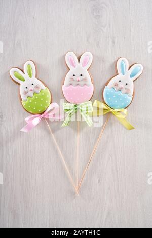 Trois biscuits au pain d'épices en forme de lapin mignon sur un bâton en bois sur fond clair. Concept de biscuits faits maison pour les vacances de Pâques. Banque D'Images