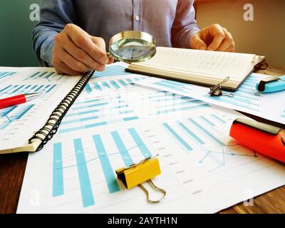 L'auditeur effectue un audit de la société financière et utilise une loupe pour vérifier le rapport. Banque D'Images