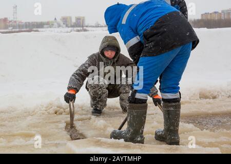Porter des vêtements de travail de protection avec une capuche sur la tête, des élingues sous le bloc de glace Banque D'Images