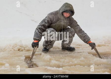 Porter des vêtements de travail de protection avec une capuche sur la tête, des élingues sous le bloc de glace Banque D'Images