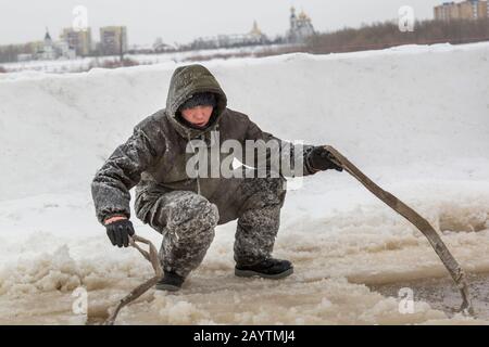 Porter des vêtements de travail de protection avec une capuche sur la tête, des élingues sous le bloc de glace Banque D'Images