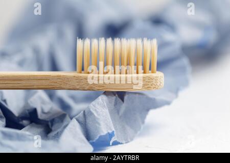 Gros plan sur une brosse à dents en bambou sur un fond blanc et violet de papier. Produits écologiques, concept zéro déchet Banque D'Images