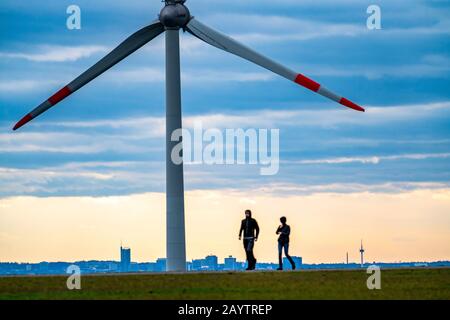 Walker sur le tas de scories de Hoheward à Herten, centrale éolienne sur le tas de scories de Hoppenbruch, vue sur les gratte-ciel d'Essen, NRW, Allemagne Banque D'Images