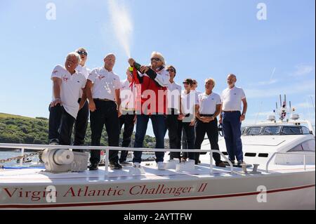 Sir Richard Branson coupe le champagne avec l'équipage original et nouveau du Challenger II Virgin Atlantic lors d'une réunion à Fowey. Banque D'Images