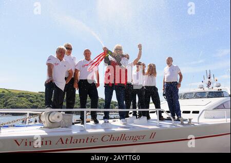 Sir Richard Branson coupe le champagne avec l'équipage original et nouveau du Challenger II Virgin Atlantic lors d'une réunion à Fowey. Banque D'Images