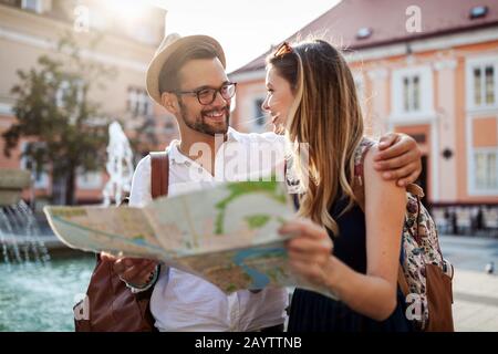 Vacances, l'amour, les rencontres et tourisme concept - smiling couple avec la carte dans la ville Banque D'Images