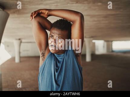 Portrait d'un jeune homme africain américain qui s'étire les mains avant de courir à l'extérieur en regardant loin Banque D'Images