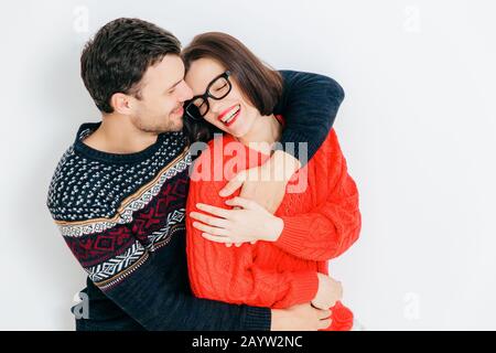 Photo de young brunette femme jouit d'temps libre avec son petit ami, a l'expression joyeuse, ferme les yeux et sourit joyeusement, isolé sur w Banque D'Images