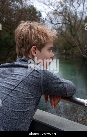 Adolescent seul sur le pont au-dessus de la rivière dans la campagne ; Penser Banque D'Images