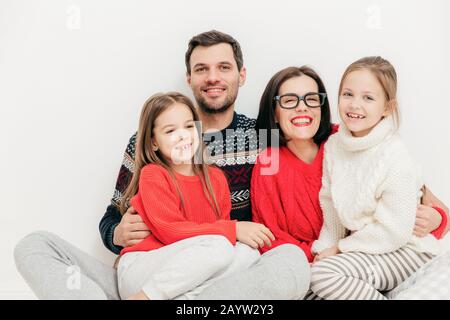 Portrait de l'homme heureux horizontal et femme embrasser leur petite filles, ont l'expression joyeuse, isolé sur fond blanc. Les enfants et les parents conc Banque D'Images