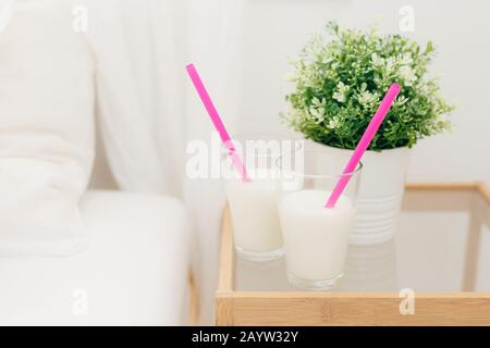 Deux verres de lait frappé Vanille sur table de chevet pour le petit-déjeuner, vase de près de plante verte, des boissons fraîches avec des pailles dans la chambre. De délicieux cocktails Banque D'Images