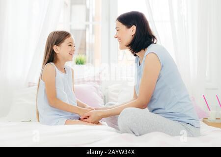 Belle Mère et fille profiter d'être ensemble, gardez la main ensemble, ont un agréable de parler, s'asseoir sur le lit confortable dans la matin, s'asseoir dans la chambre à coucher, ont g Banque D'Images