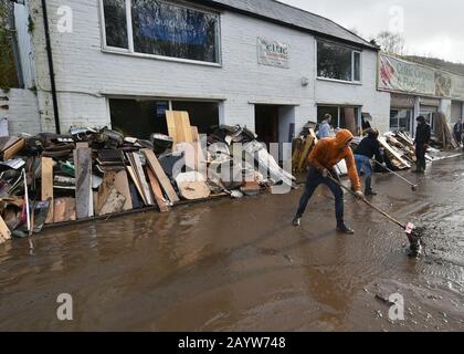 Les membres du personnel qui nettoyaient à l'extérieur du magasin Celtic Flooring, endommagé par les inondations à Nantgarw, au sud du Pays de Galles, où les résidents retourneront dans leur maison pour étudier et réparer les dégâts à la suite de la tempête Dennis. Banque D'Images