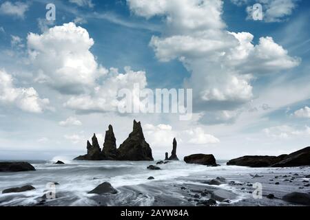 Magnifique paysage avec des formations de roches basaltes Troll Orteils sur la plage noire, les vagues de l'océan et le paysage nuageux. Reynisdrangar, Vik, Islande Banque D'Images