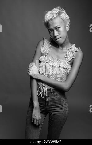 Jeune belle femme rebelle avec des cheveux courts sur fond gris Banque D'Images