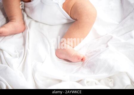 Les jambes de bébé et le bas en couche sur fond de lit blanc, vue du dessus, copy space Banque D'Images