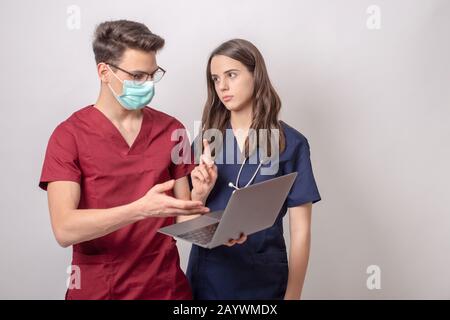 deux jeunes médecins avec ordinateur portable isolé sur blanc Banque D'Images