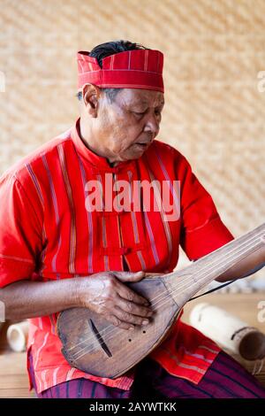 Un Homme Du Groupe Ethnique De Kayah Jouant Une Guitare Comme Instrument, Hta Nee La Leh Village, Loikaw, Kayah State, Myanmar. Banque D'Images