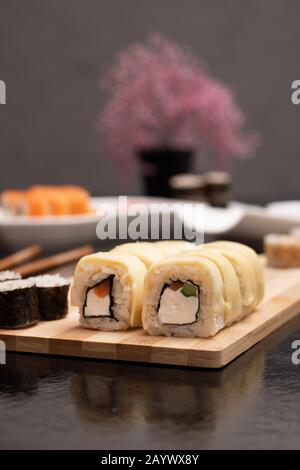 Sushi Set sashimi et petits pains à sushi sur fond sombre, arbre sakura flou Banque D'Images