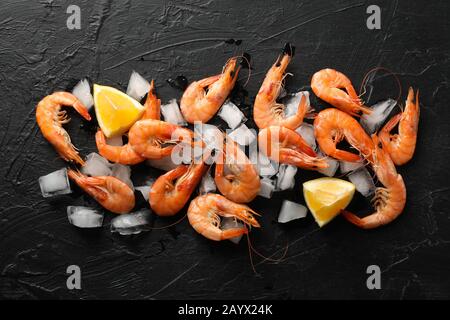 Crevettes, citron et glace sur fond noir, vue de dessus Banque D'Images