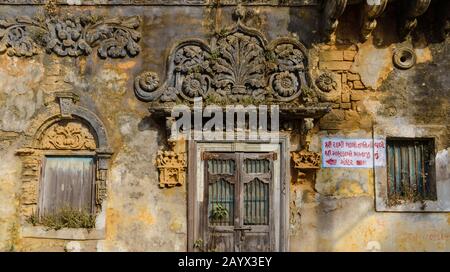 Le détail orné sur une belle porte délavée, des murs de briques et la façade d'un vieux temple dans Diu. Banque D'Images