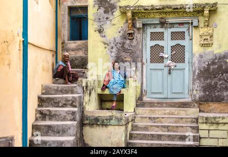 Une vieille femme indienne se trouve à l'extérieur de la porte d'une ancienne maison dans les rues de l'île De Diu . Banque D'Images