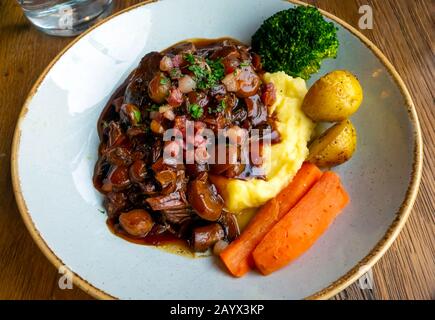 Déjeuner au café un plat de bœuf bourguignon avec purée et de nouvelles carottes de pommes de terre et brocolli dans un restaurant de style français Banque D'Images
