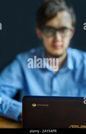Bishkek, Kirghizstan - 6 Juin 2019: Asus Chromebook. Un jeune homme d'affaires intelligent travaillant sur un ordinateur portable au bureau. Sourire et regarder l'appareil photo Banque D'Images