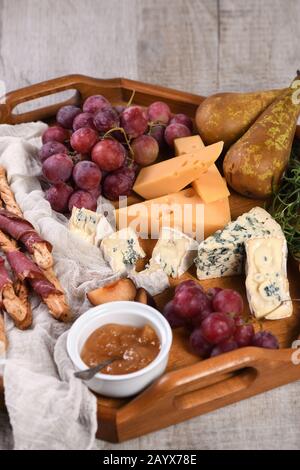 Antipasto. Plat avec du gruissini croustillant enveloppé de bacon séché, tranches de fromage brie, camembert, fromage bleu et raisin de muscat avec fruits Banque D'Images