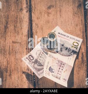 Billets écossais et livres de monnaie en livre sterling sur fond de bois. Banque D'Images