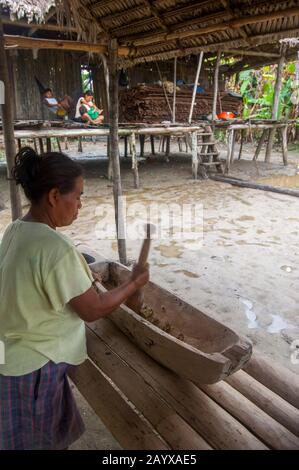 Une femme prépare du manioc dans une maison sur pilotis dans un village le long de la rivière Maranon dans le bassin de la rivière Amazone péruvienne près d'Iquitos. Banque D'Images