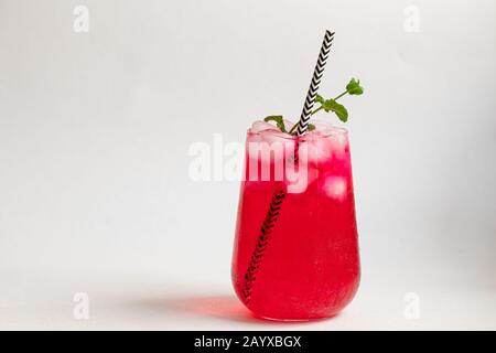 Boisson aux framboises et aux baies dans un verre transparent avec de la glace. Ajout de branches de palmiers et de framboises. Fond blanc. Espace de copie Banque D'Images