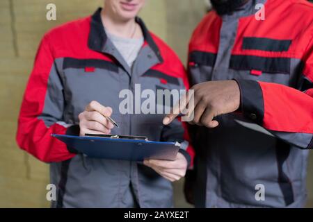 Photo horizontale de l'homme et de la femme non reconnaissables travaillant ensemble en usine en faisant des documents administratifs ensemble Banque D'Images