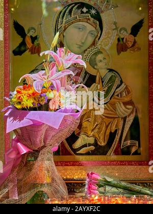 Un bouquet de fleurs, de roses et de bougies devant une photo de la mère Marie avec Jésus, située à l'église de Binondo à Manille, aux Philippines Banque D'Images