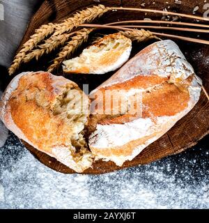 Le pain frais croustillant maison fait de farine blanche se trouve sur une planche ronde à côté de la farine Banque D'Images