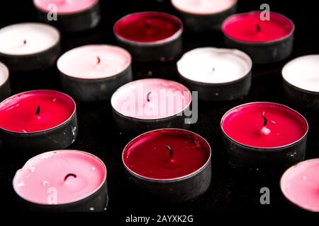 Un ensemble de bougies de paraffine chauffe-plat rose sur fond noir. Banque D'Images