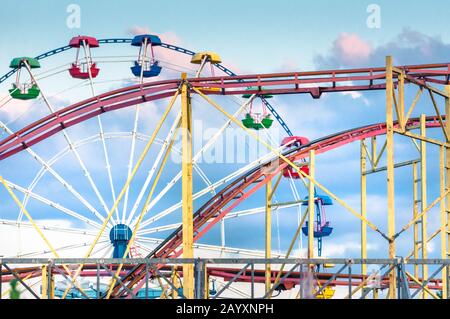 Vue abstraite d'un ancien parc d'attractions abandonné avec une roue ferris et des montagnes russes Banque D'Images