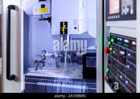 Une fraiseuse verticale CNC 4 axes moderne fonctionnant avec le refroidissement par eau, mise au point sélective sur l'arrière-plan Banque D'Images