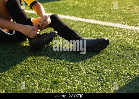 Vue rapprochée du joueur de football mettant sur ses chaussures Banque D'Images