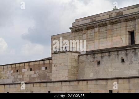 Les gens qui se tiennent sur le podium Adolf Hitlers dans le grand-stand dominant les terrains de rassemblement nazis, Nuremberg, Allemagne. Banque D'Images