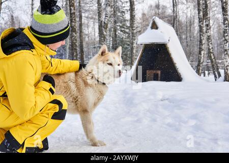 la jeune femme communique avec un chien husky dans la forêt hivernale Banque D'Images