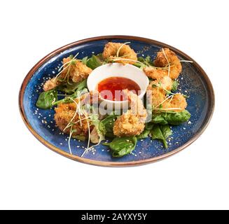 crevettes au maïs soufflé avec sauce au ketchup sur une plaque bleue, isolées sur fond blanc vue latérale Banque D'Images