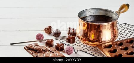 Bonbons ou pralines au chocolat de luxe faits à la main, accompagnés d'un pot en cuivre rempli de chocolat fondu et de moules pour bonbons en forme de coeur pour les Valentines dans un Banque D'Images